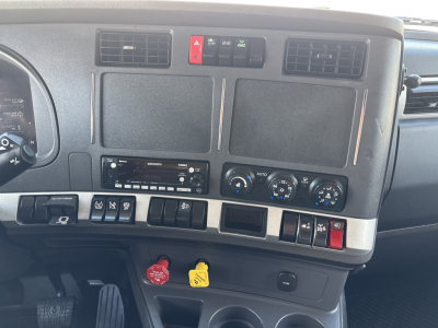 Kenworth T680 dashboard and center console showing four blank screens, controls, and a red hazard switch with climate and radio panel.