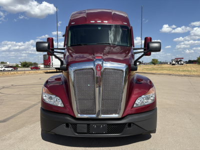 Kenworth T680 front view showing chrome grille, headlights, and emblem, red in color, in a parking lot.