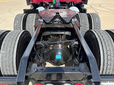 Kenworth T680 rear undercarriage showing dual rear axles, chassis, differential with blue tag, and mounting hardware.