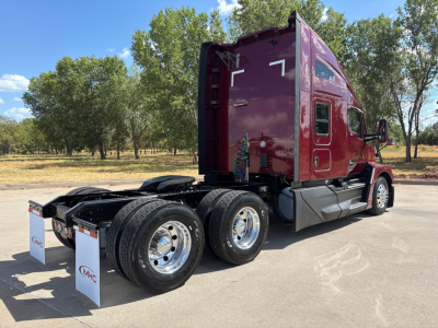 Kenworth T680 tractor cab side and rear view showing dual rear axles, maroon cab, metal steps, and trailer hitch area with mud flaps.
