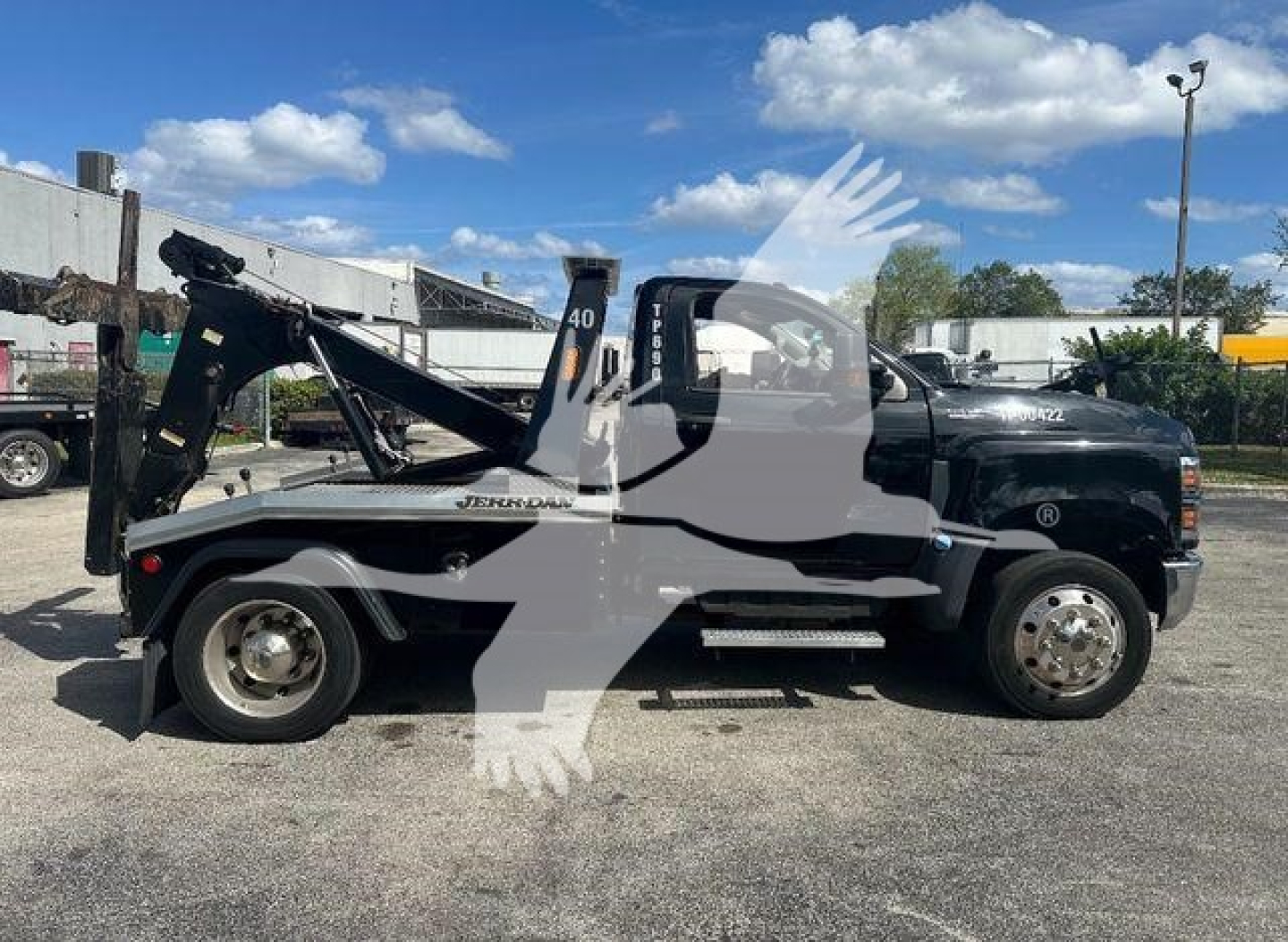 Truck side view showing a tow/boom wrecker with black cab, white lettering 'JERK' style on the bed, and a mounted hydraulic winch arm. Side mirrors visible, wheel rims chrome.