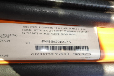 VIN label showing Federal Motor Vehicle Safety Standards statement, VIN 4V4M19DG0CN550272, barcode, and classification text; part of a vehicle identification plate on an orange surface.