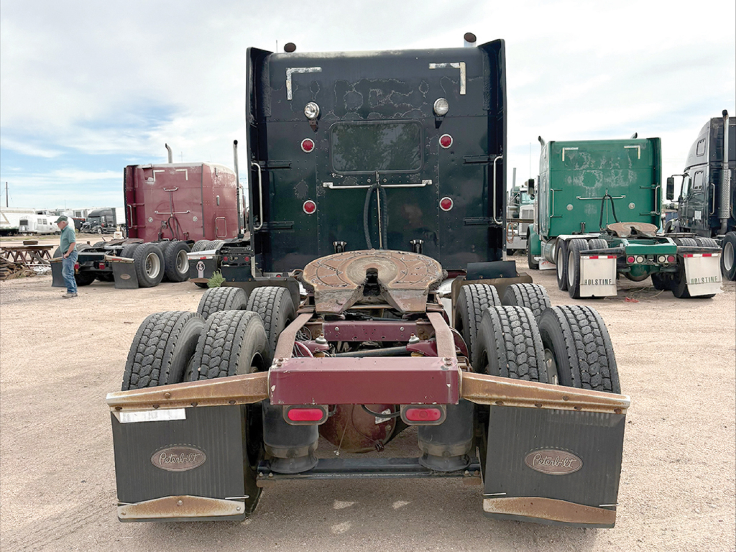 Peterbilt 379 UltraCab extended hood tractor rear view showing dual rear axles and mud flaps with Peterbilt logos