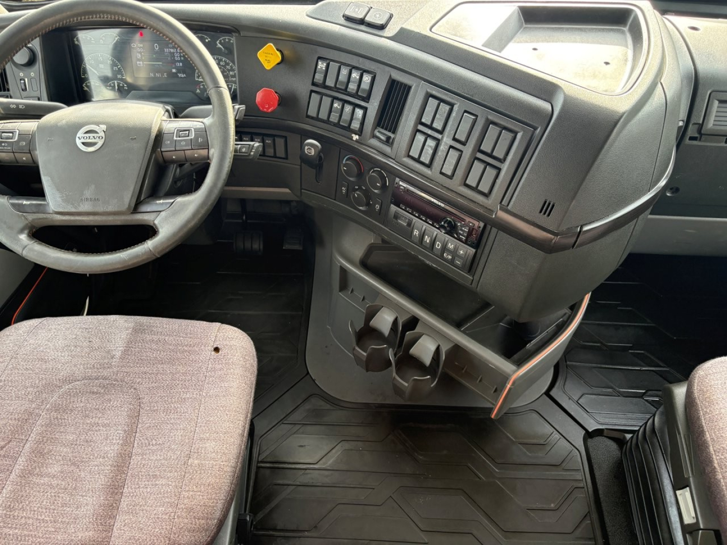 Dashboard and steering wheel area of a 2019 Volvo VNR sleeper cab showing steering wheel, control panel, and cup holders.