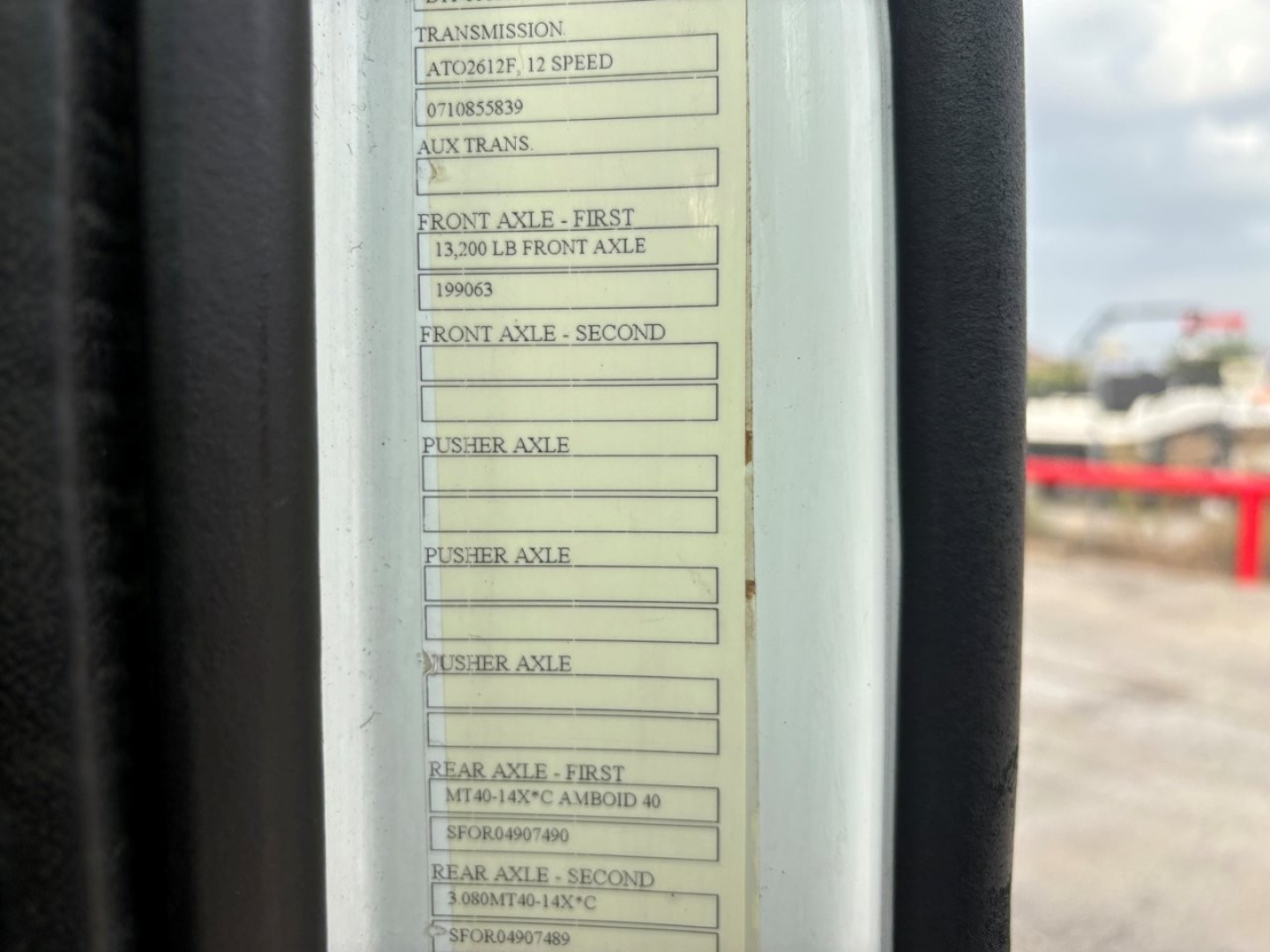 Truck door jamb specification labels showing transmission, front axle, and rear axle ratings on a Volvo VNR model. Text includes 'FRONT AXLE - FIRST 13,200 LB FRONT AXLE' and other axle data.