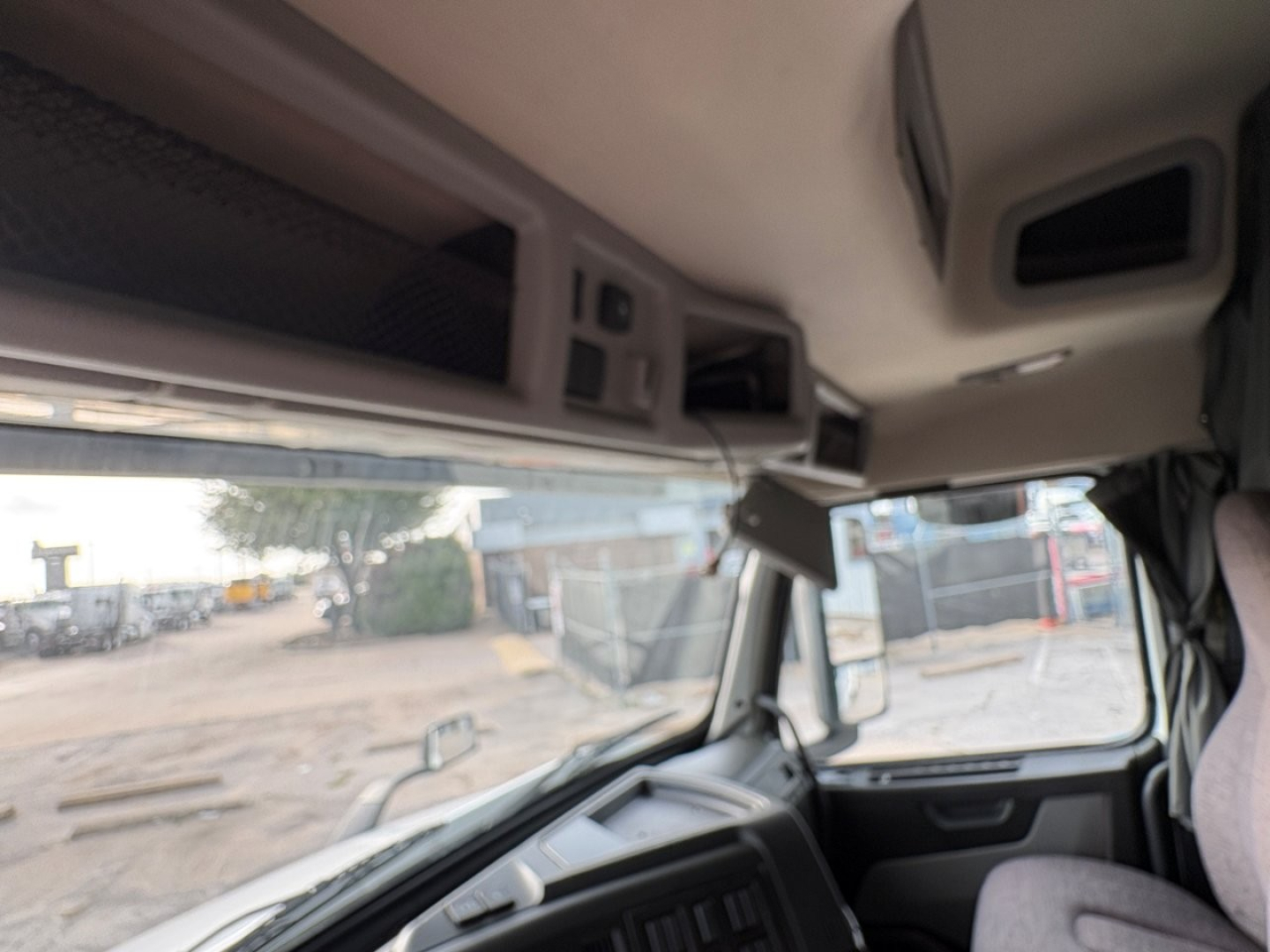 Truck interior overhead area with control panel and sun visor, windshield view of yard outside