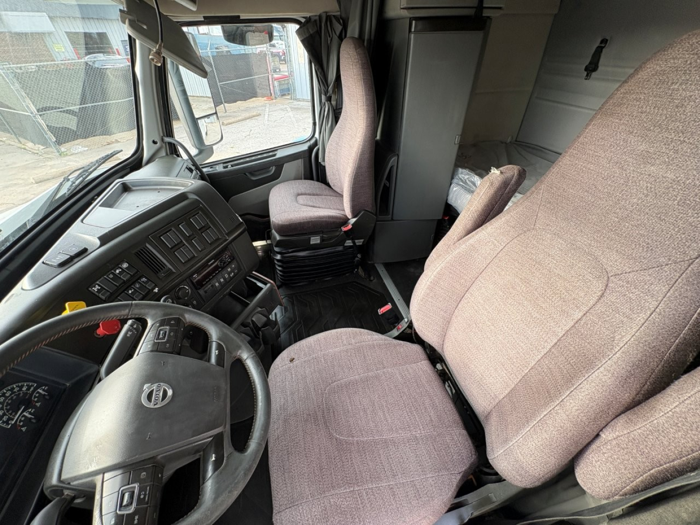 Volvo VNR64T640 truck cab interior showing driver seat and passenger seat with dashboard, steering wheel, and window view.