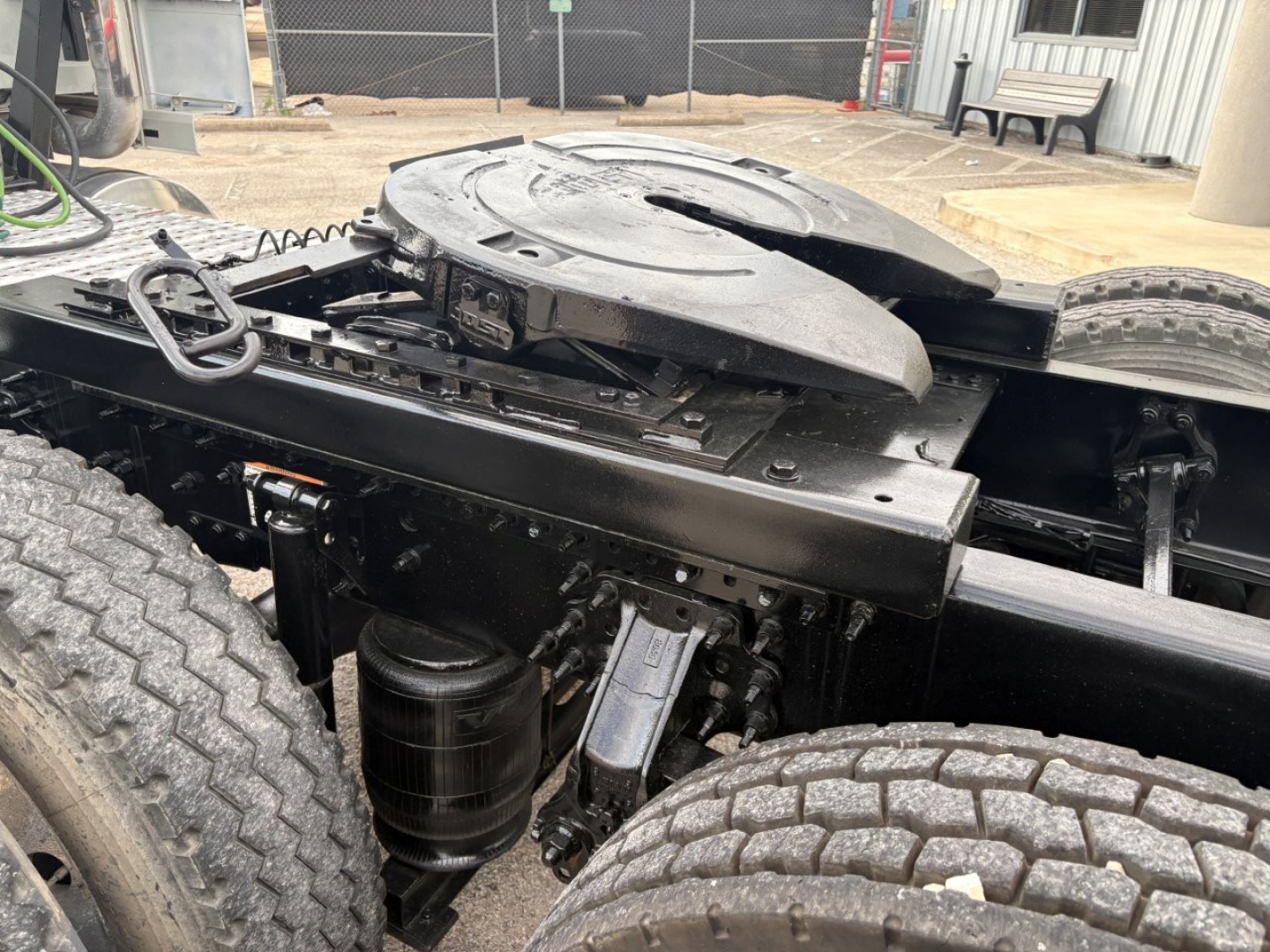 Truck chassis with fifth wheel plate and air tanks visible; components in view include air lines, suspension, fuel tank, and wheel treads.