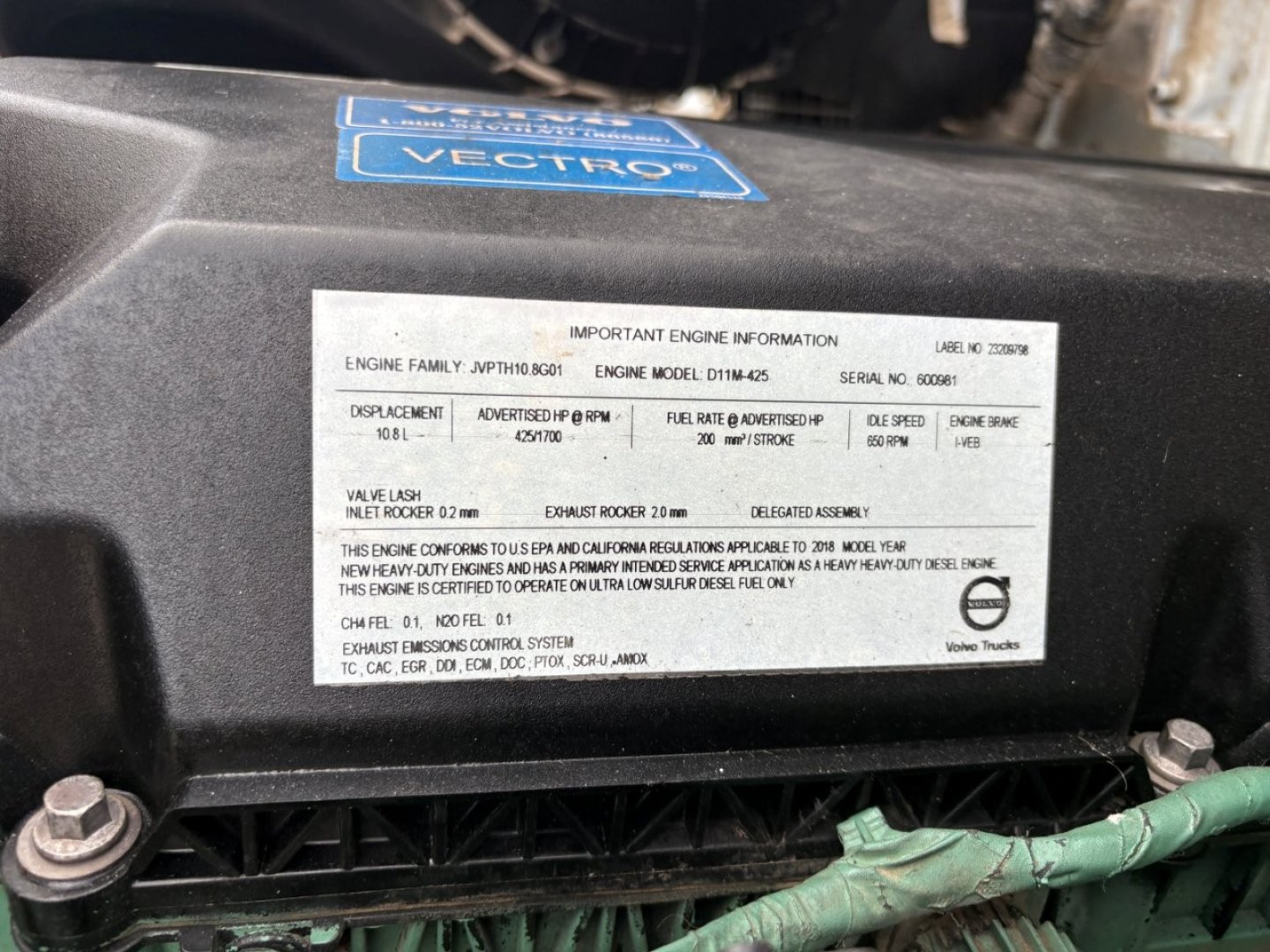 Engine compartment label with 'Important Engine Information' and serial numbers; blue Vectro label on top of black engine cover; several lines of small text detailing engine family, displacement, oil etc.