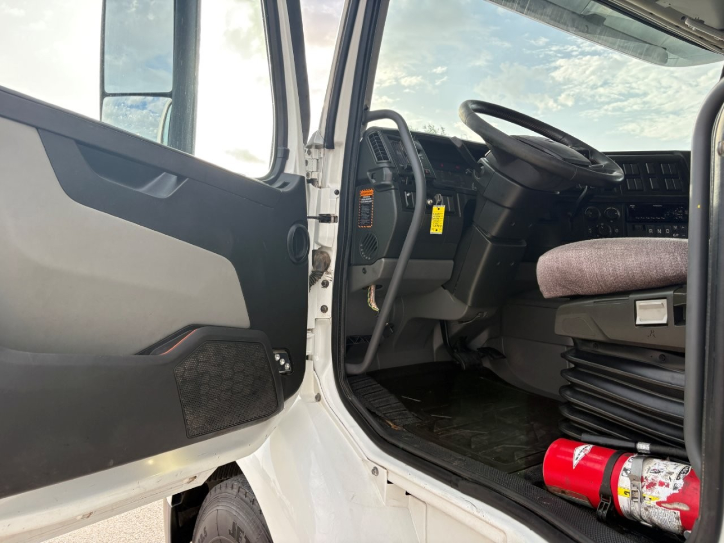 Interior of a 2019 Volvo VNR64T640 cab showing front driver seat and steering wheel with door open.