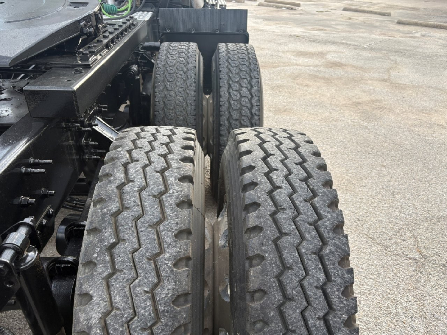 Truck rear dual tires and chassis of a 2019 Volvo VNR64T640 conventional sleeper showing triple axles and tire tread.