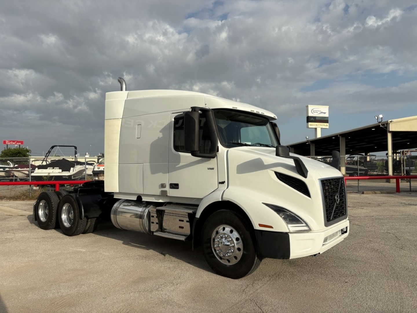 Volvo VNR64T640 sleeper cab truck in a lot, front-left-side view; white exterior, chrome fuel tanks, dual rear axles visible