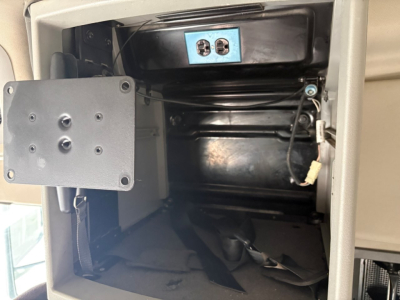 Volvo engine bay/sleeper area with open storage compartment showing blue control panel and wiring harness in the foreground.