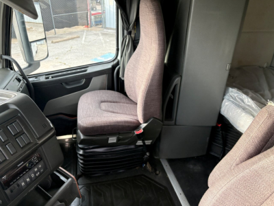 Cab interior of a 2019 Volvo VNR64T640 truck showing the driver seat and passenger seat, with dashboard, steering wheel, and a glimpse of sleeper area.