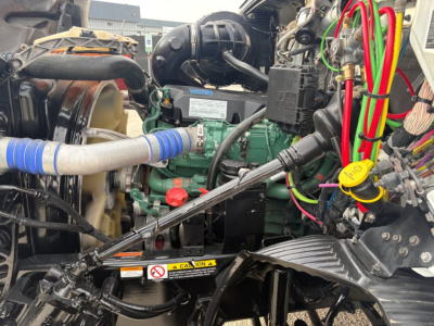Engine bay of 2019 Volvo VNR64T640 showing green engine, radiator hose, yellow oil cap, and wiring harnesses with labels.