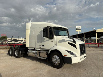 Volvo VNR64T640 sleeper cab truck in a lot, front-left-side view; white exterior, chrome fuel tanks, dual rear axles visible