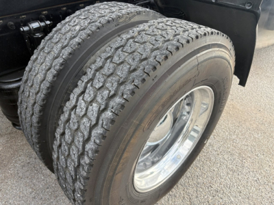 Truck wheel close-up showing dual rear tire with tread pattern and chrome rim, part of Volvo VNR64T640 sleeper cab.