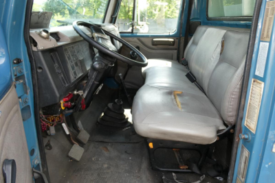 Truck cab interior of a 2002 International 4700 showing steering wheel, dashboard, and front bench seat.
