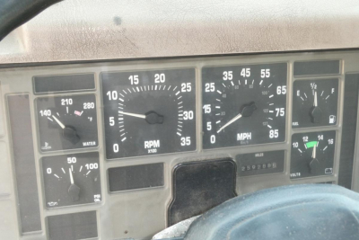 Dashboard cockpit of a 2002 International 4700 showing analog gauges including RPM, speedometer, and various indicator lights