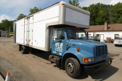 Box truck with a blue cab and white cargo box showing a raised box body on a paved lot.
