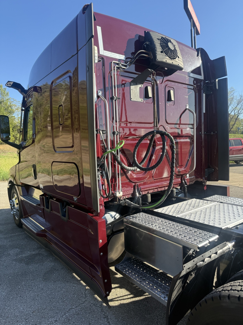 Rear and side view of a maroon 2021 Freightliner Cascadia 126 truck sleeper with exposed wiring and a metal steps platform; no legible labels visible on the image itself.