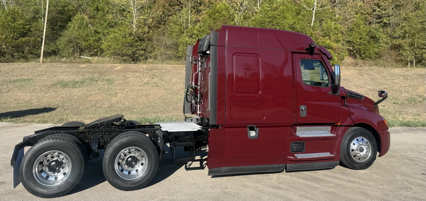Freightliner Cascadia 126 semi truck side view showing red cab and dual rear axles.