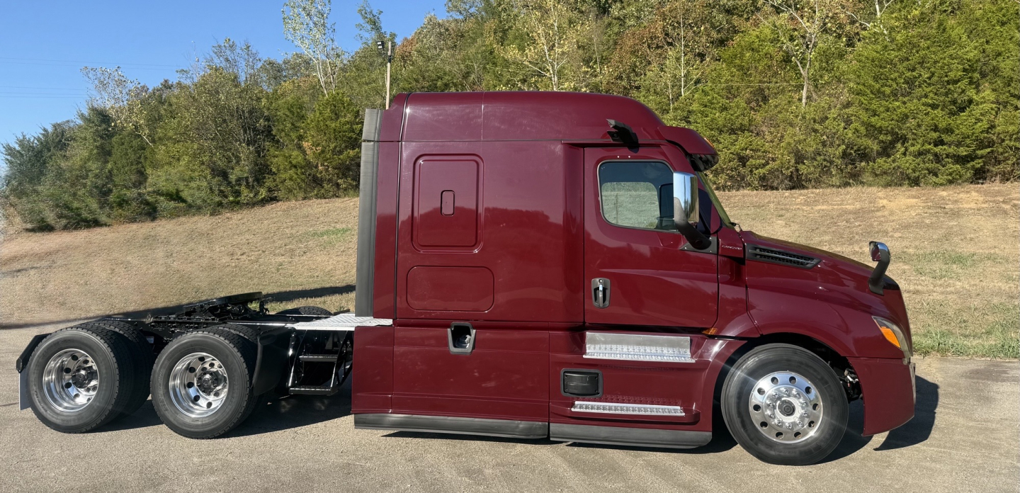 Freightliner Cascadia 126 sleeper tractor side view showing red cab and black chassis, dual rear axles, chrome steps and fuel tanks.