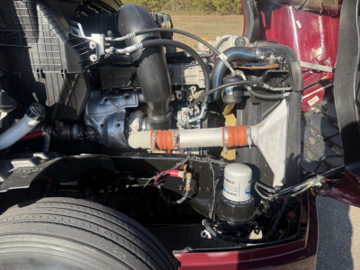 Freightliner Cascadia 126 engine bay showing intake hoses, coolant lines, air filter canister, and auxiliary components.