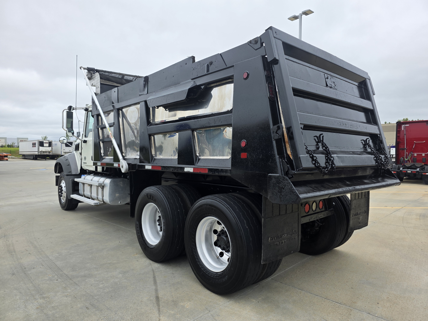 Dump truck rear view showing dump bed with tailgate and dual rear axles on a Mack Granite solid-wheel configuration.