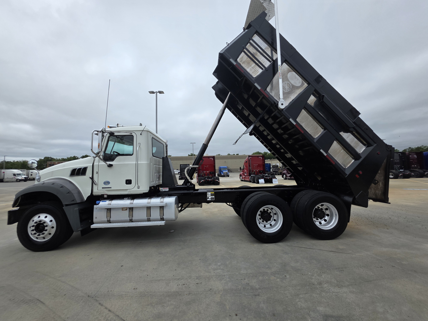 Truck chassis with a raised dump bed on a Mack Granite dump truck showing hydraulics and rear wheels.