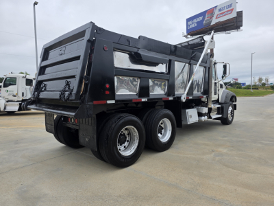 Truck: 2021 Mack GRANITE dump truck with black dump bed, rear view showing dual rear axles, side cab, and hydraulic components; visible text on truck features and surroundings.