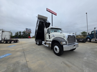 Mack GRANITE dump truck with raised dump bed in a dealership lot.