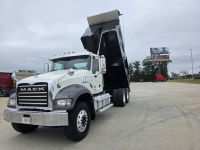 Mack Granite dump truck with raised bed in a parking lot; visible text on the truck includes MACK on the grille and a license plate; no other legible labels.