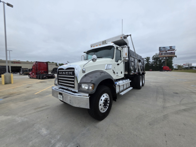 Mack Granite dump truck in a parking lot, front-left view showing chrome bumper, grille with MACK emblem, white cab, and dump body.