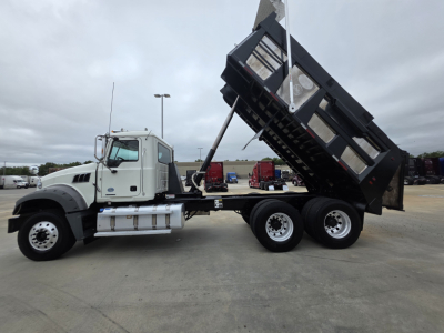 Truck cab and dump bed in raised dump position, Mack GRANITE chassis with triple rear axles and steel dump body visible, side view.