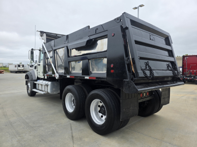 Dump truck rear and side view showing dump bed and rear tires of a Mack Granite dump truck.