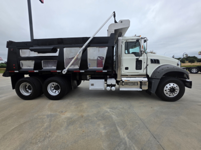 Truck side view showing a Mack GRANITE dump truck with a black dump body and white cab, VIN plate area not legible.