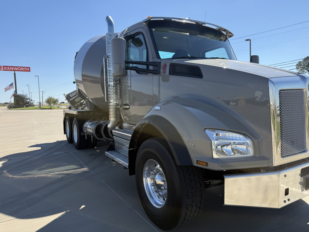 Kenworth mixer truck 2026 T880 side view showing front grille, chrome bumper, fuel tanks, step rungs, dual rear wheels, and mixer drum.