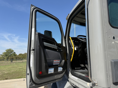 Truck cab interior with open door showing driver seat and dashboard. Visible labels on door panels and window views.