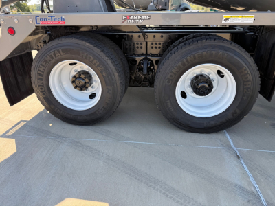 Kenworth T880 mixer truck rear dual wheels showing Continental tires and white steel rims, frame rails with on-tech badge and Extreme Duty sticker.