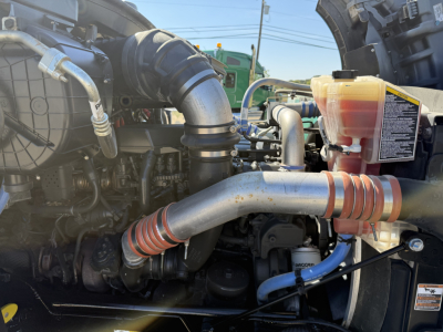 Kenworth T880 engine bay showing air intake, hoses, and coolant reservoir with warning label.