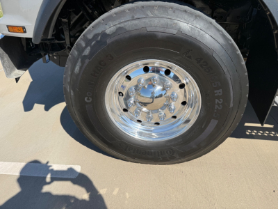 Kenworth T880 front wheel with tire markings visible: 'Cooper' tire brand and '425/65R22.5' size, chrome hubcap, parts of wheel well and fender.