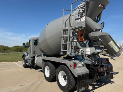 Kenworth T880 mixer truck rear view showing cement mixer drum and chute with ladder and hydraulic components.