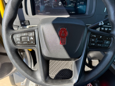 Kenworth T880 steering wheel with KW emblem; dashboard controls visible on left and right, center lower dash area.