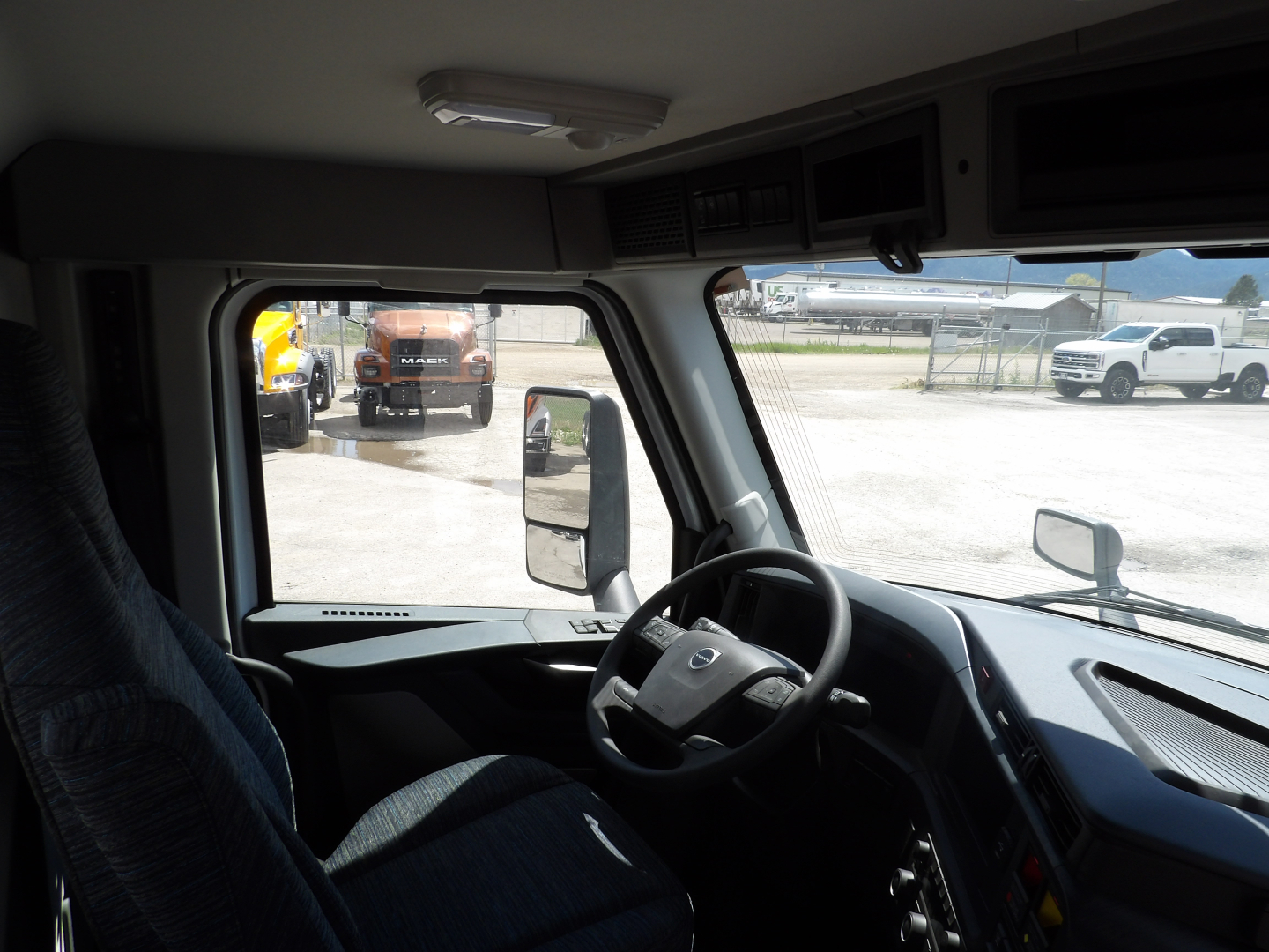 Volvo VNL64T300 truck cab interior showing steering wheel dashboard and driver seat with windows and side mirrors.
