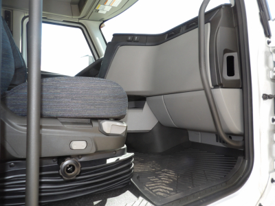 Cab interior of a Volvo VNL truck showing driver seat and open door with floor mat and dashboard detail.
