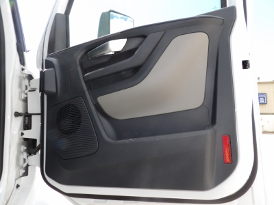 Truck interior door panel view showing black and gray plastics, speaker grille, window crank area, and red reflective marker.