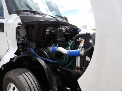 Volvo VNL64T300 engine bay view showing turbo hose, intercooler piping, blue silicone hoses, engine block, and front wheel well.
