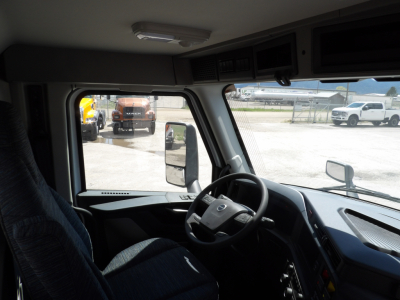 Volvo VNL64T300 truck cab interior showing steering wheel dashboard and driver seat with windows and side mirrors.