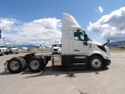 Volvo VNL64T300 tractor side view showing tandem rear axles and sleeper cab with white paint.